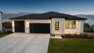 Contemporary home with a mountain view, stone siding, a garage, concrete driveway, and roof with shingles