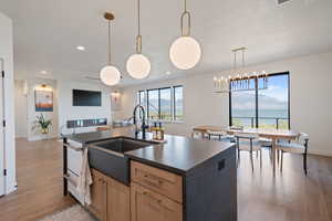 Kitchen with light wood-type flooring, a kitchen island with sink, light brown cabinets, pendant lighting, and recessed lighting