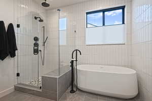 Bathroom with a freestanding tub, a shower stall, tile walls, and tile patterned flooring
