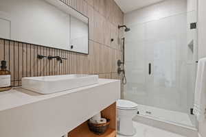 Full bathroom featuring a stall shower, vanity, and tile walls