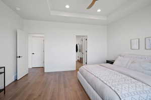 Bedroom featuring a tray ceiling, wood finished floors, recessed lighting, and a ceiling fan