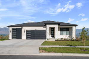 View of front of house with a mountain view, stone siding, a garage, and driveway