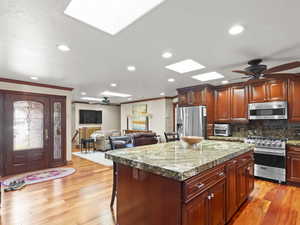 Kitchen with a ceiling fan, a kitchen breakfast bar, a skylight, open floor plan, and a kitchen island