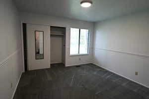 Unfurnished bedroom with dark carpet and a closet