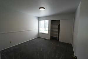 Unfurnished bedroom with dark colored carpet and a closet