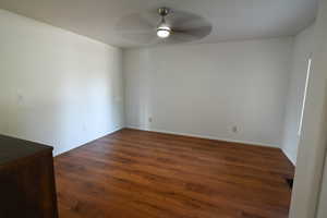 Unfurnished room with dark wood finished floors and ceiling fan