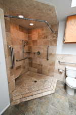 Bathroom featuring a shower stall and tile walls