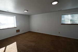 Empty room with dark colored carpet and a textured ceiling