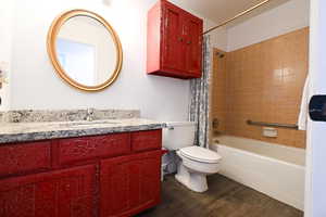 Full bath featuring shower / bath combination with curtain, dark wood-style floors, and vanity