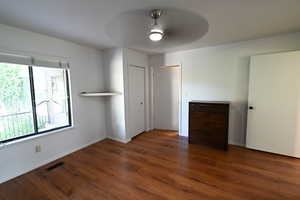 Unfurnished bedroom featuring dark wood finished floors and a ceiling fan
