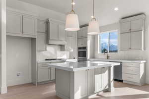 Kitchen featuring hanging light fixtures, tasteful backsplash, stainless steel appliances, light wood-type flooring, and a kitchen island