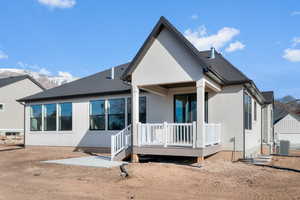 Back of house with a patio area, a deck with mountain view, a shingled roof, and stucco siding