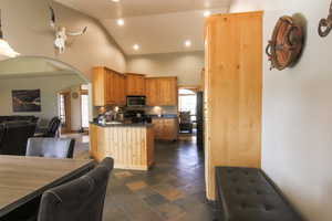 Kitchen with open floor plan, arched walkways, dark countertops, black appliances, and recessed lighting