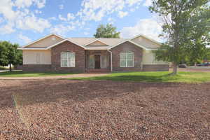 Ranch-style house with brick siding, a porch, a shingled roof, and a front lawn