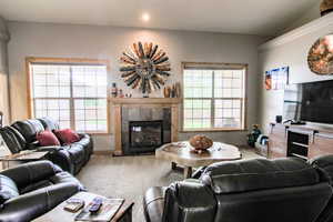 Living room with a tiled fireplace, plenty of natural light, carpet floors, and recessed lighting