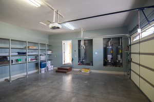 Garage featuring gas water heater, a garage door opener, and heating unit