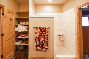 Full bath featuring a tile shower and dark tile patterned flooring