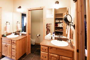 Bathroom featuring two vanities and dark tile patterned floors