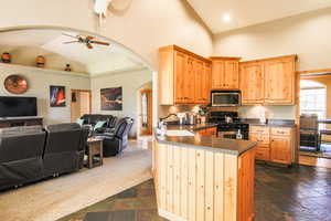 Kitchen featuring open floor plan, gas range, arched walkways, stainless steel microwave, and a peninsula