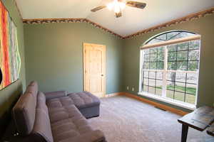 Living area featuring lofted ceiling, carpet, and a ceiling fan