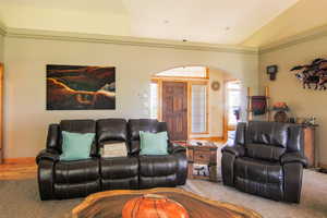 Carpeted living area featuring arched walkways and ornamental molding