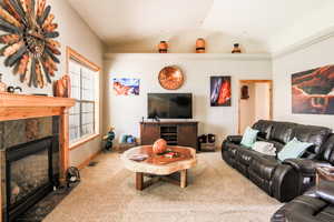Living area featuring a fireplace, vaulted ceiling, and carpet