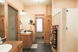 Bathroom with two vanities, a walk in shower, and dark tile patterned flooring