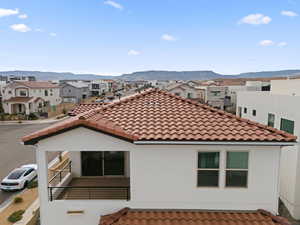 Back of house with a tile roof, a residential view, stucco siding, and a mountain view