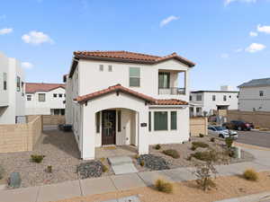 Mediterranean / spanish-style house with a balcony, stucco siding, a tile roof, and a residential view