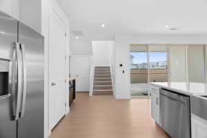 Kitchen with stainless steel appliances, light wood-type flooring, white cabinetry, and recessed lighting