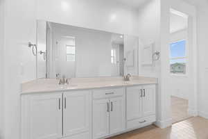 Bathroom with double vanity and light wood-type flooring