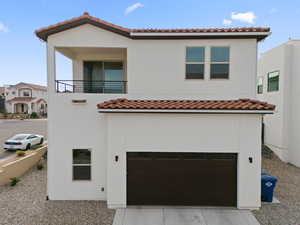 View of front of property featuring a tiled roof, a balcony, a garage, stucco siding, and concrete driveway