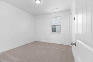 Empty room featuring light carpet and baseboards