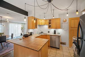 Kitchen with a peninsula, glass insert cabinets, backsplash, black appliances, and tile counters