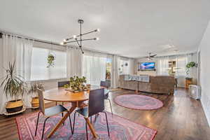 Dining room featuring dark wood-style floors, a textured ceiling, ceiling fan, and a chandelier