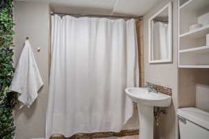 Full bath featuring a textured wall and a stall shower