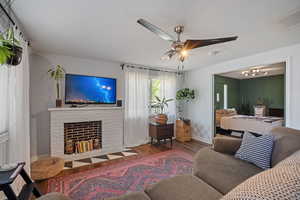 Living area featuring wood finished floors, a fireplace, and ceiling fan