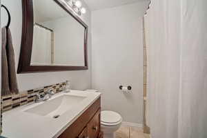 Full bath featuring vanity, light tile patterned floors, backsplash, and a shower with shower curtain
