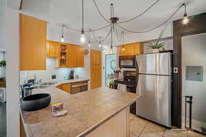Kitchen featuring black appliances, hanging light fixtures, backsplash, and a peninsula