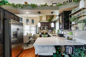 Kitchen featuring appliances with stainless steel finishes, a peninsula, light stone countertops, and pendant lighting