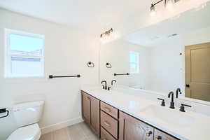 Full bath with double vanity and light tile patterned flooring