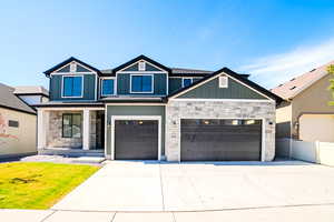 View of front of house featuring stone siding, board and batten siding, driveway, and covered porch