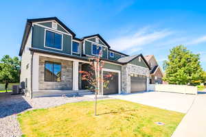View of front of house with stone siding, driveway, covered porch, and a garage