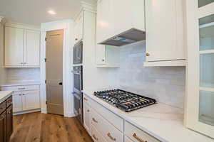 Kitchen with white cabinetry, light wood-style flooring, backsplash, and recessed lighting