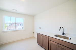Laundry room with light carpet, washer hookup, and cabinet space