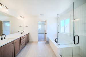 Full bathroom with a garden tub, double vanity, light tile patterned floors, and a stall shower