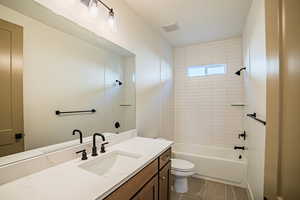 Bathroom with washtub / shower combination, vanity, and dark tile patterned floors
