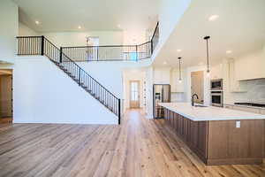 Kitchen with recessed lighting, tasteful backsplash, stainless steel appliances, light wood-type flooring, and white cabinets