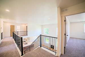 Hallway with carpet, an upstairs landing, and recessed lighting