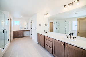 Full bathroom with double vanity, a stall shower, light tile patterned floors, and healthy amount of natural light